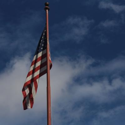 An American flag against a blue sky with white clouds.