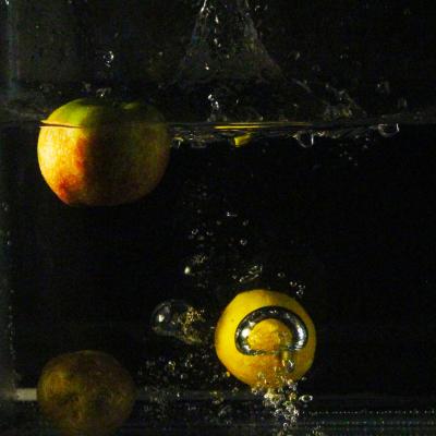 Dark image of fruit splashing into a tank of water. 